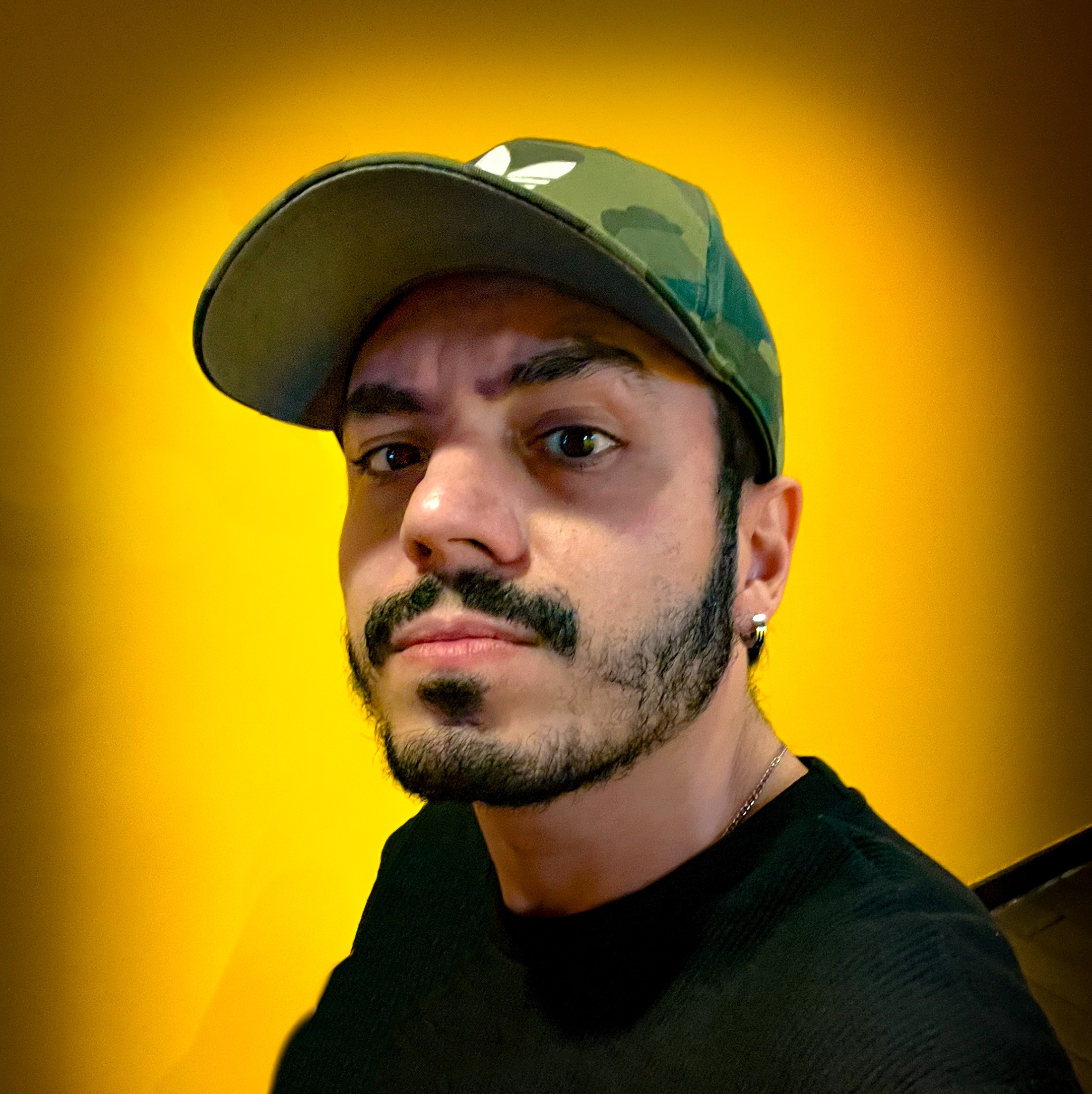 Retrato de Dre Rendón con gorra sobre fondo amarillo