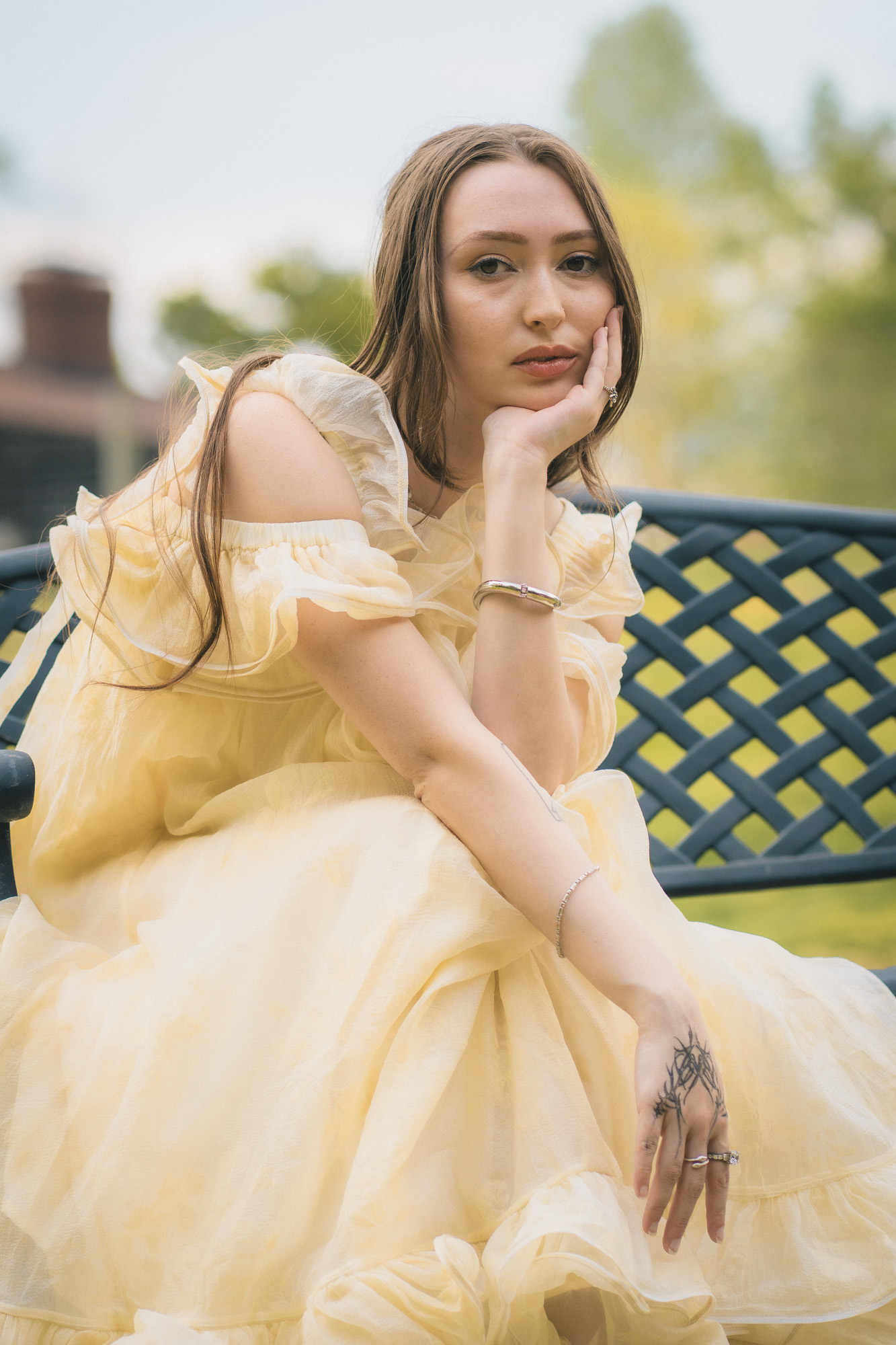 Mujer con vestido amarillo de hombros descubiertos sentada en una banca